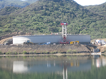 A mobile construction tower applies the first layer of concrete coating material to protect the pre-stress cables surrounding the tank.