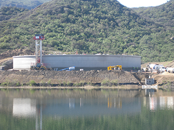 A mobile construction tower applies the first layer of concrete coating material to protect the pre-stress cables surrounding the tank.