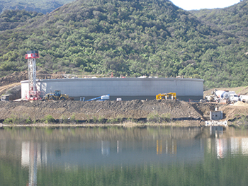 A mobile construction tower applies the first layer of concrete coating material to protect the pre-stress cables surrounding the tank.